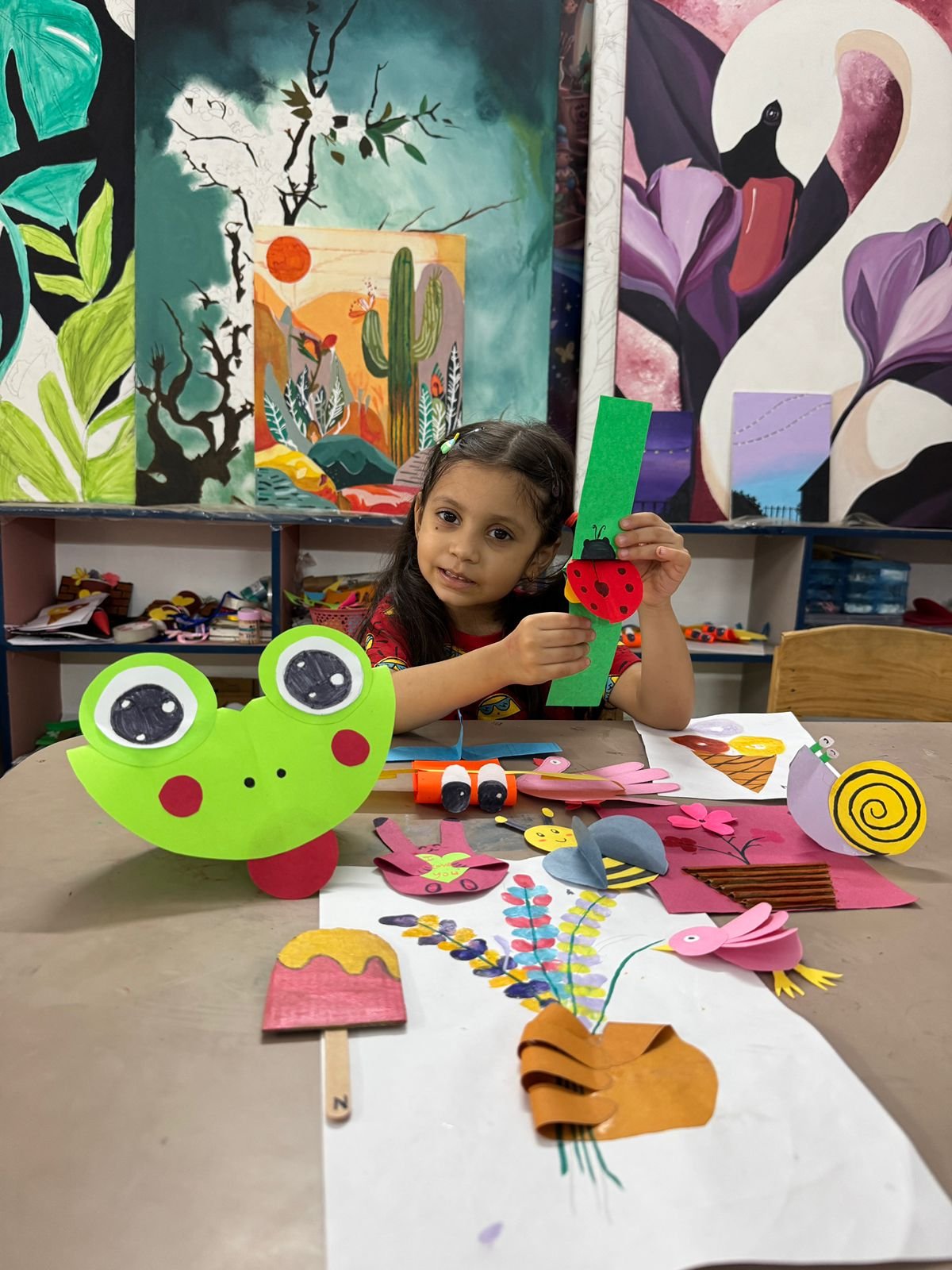 A girl proudly presenting her paper craft frog and ladybug