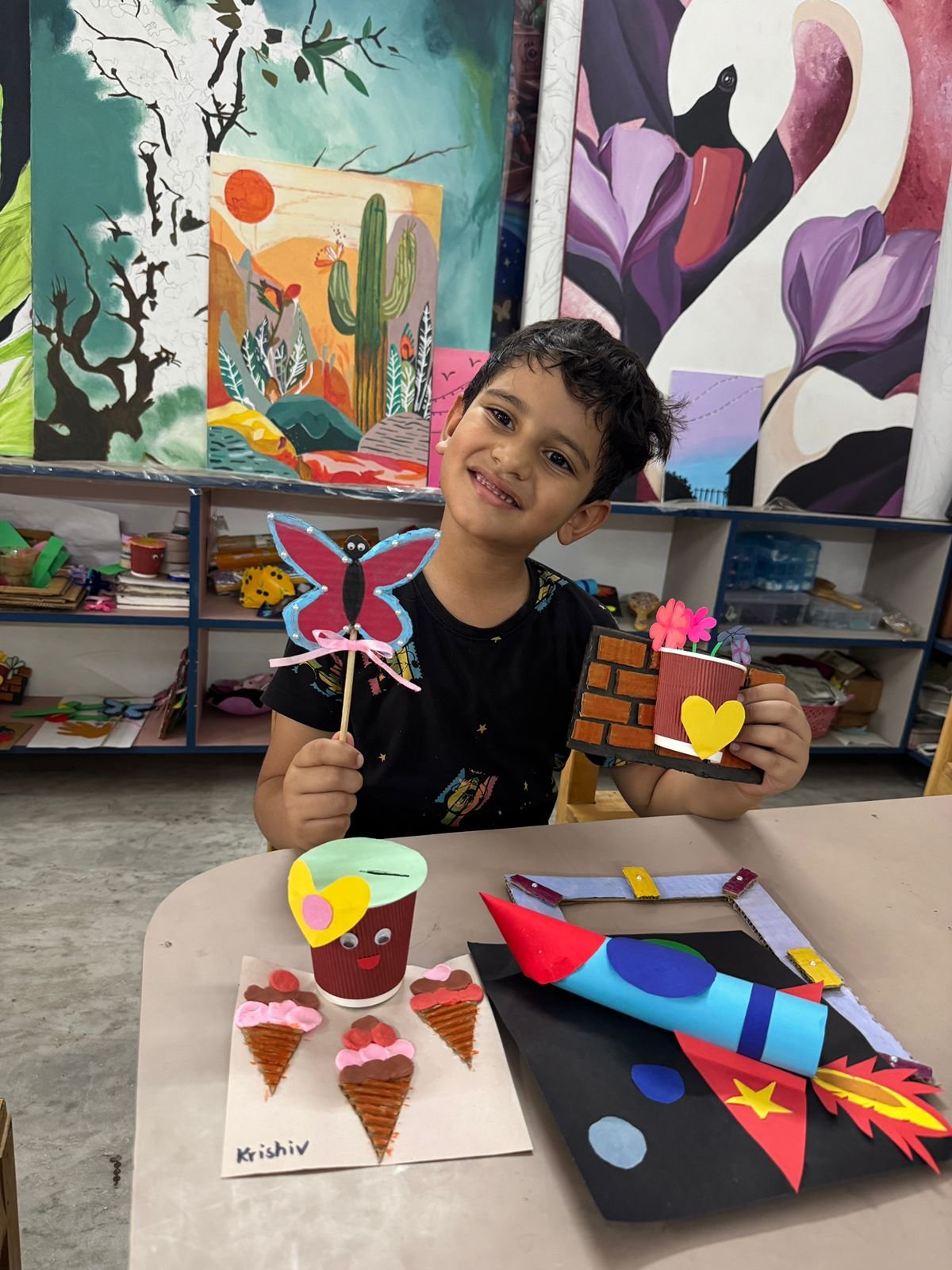 A boy holding his hand-painted butterfly and flower pot craft