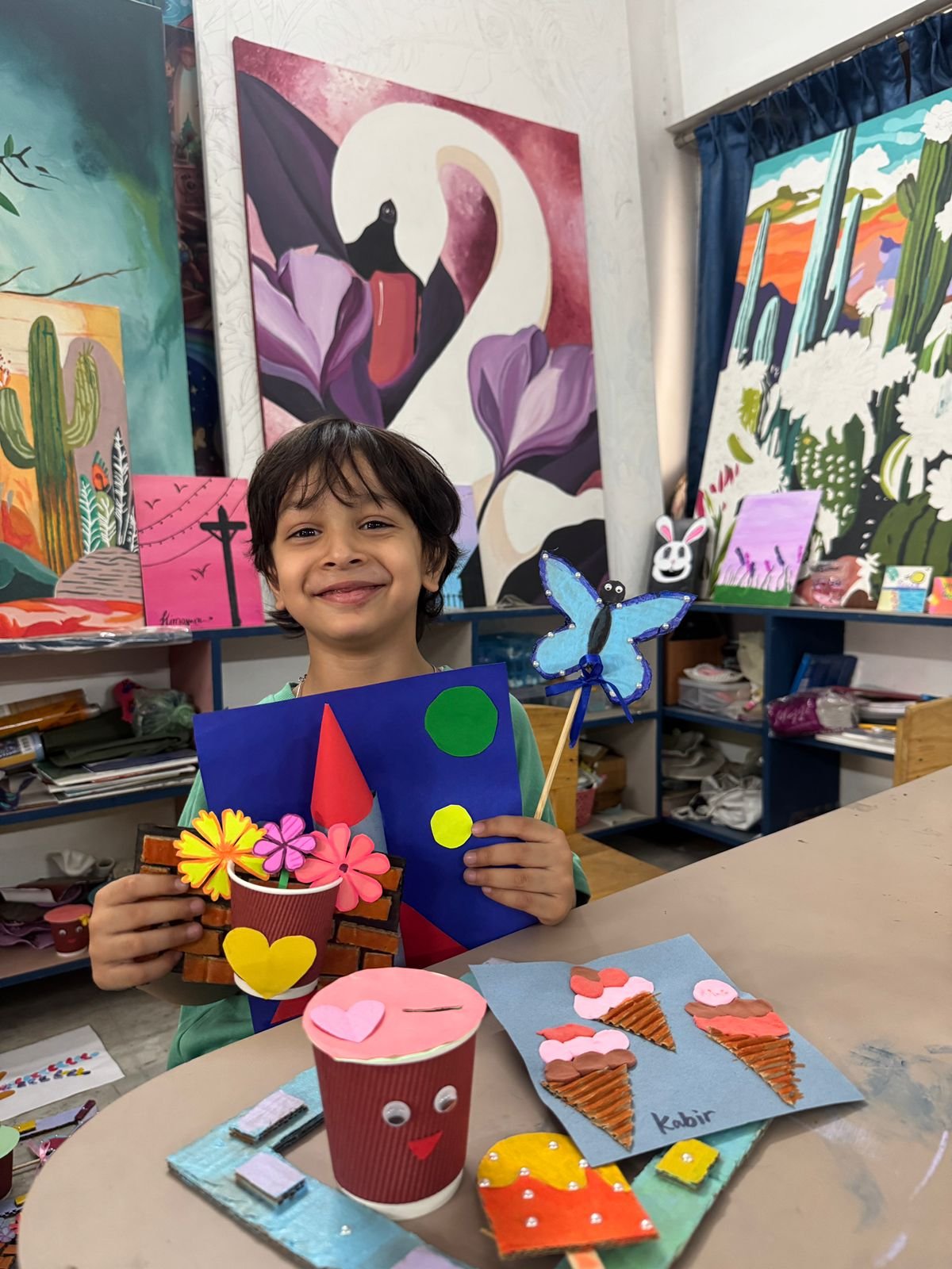 A boy holding his paper flower pot and butterfly craft