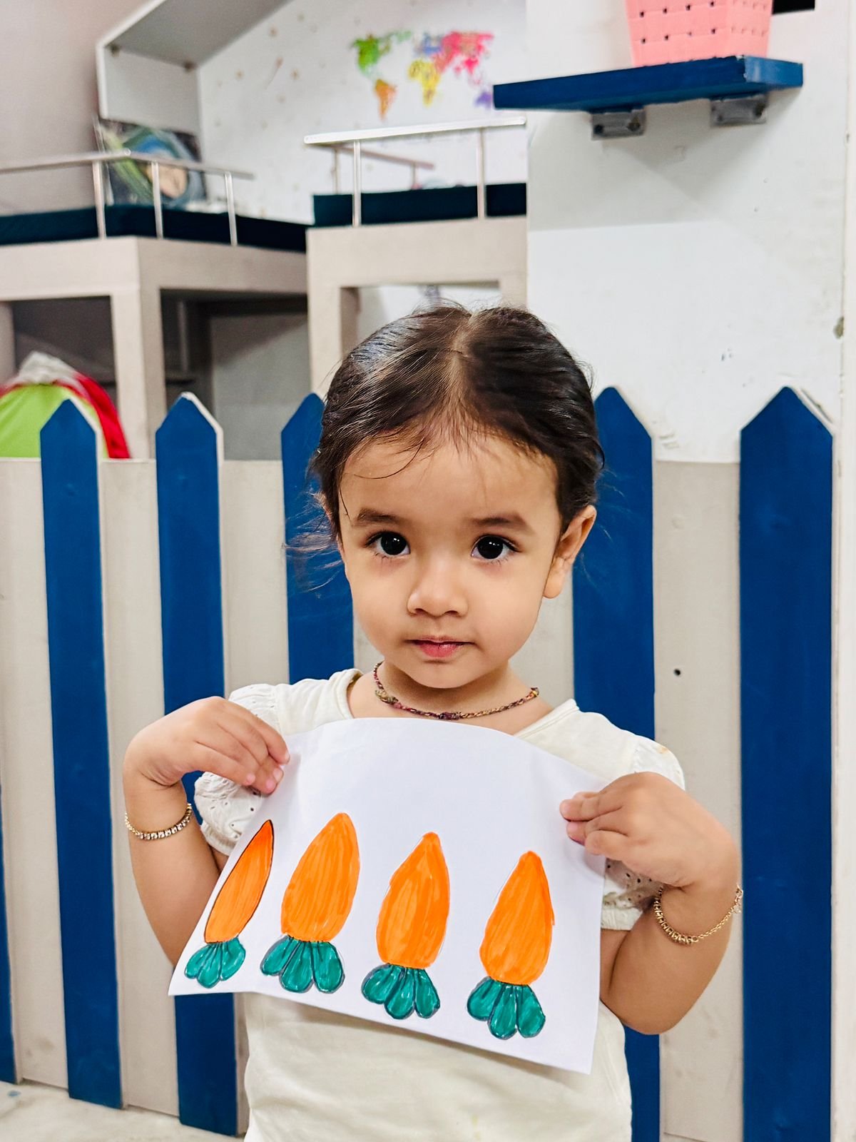 A toddler proudly holding her hand-drawn flower artwork