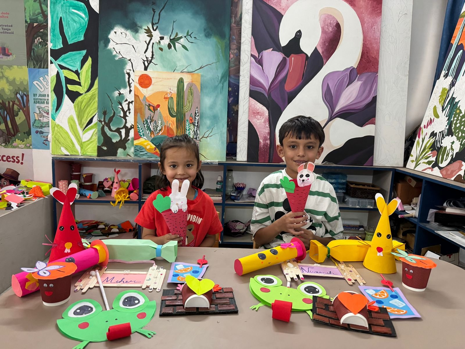 Two children with their handmade bunny and frog paper crafts